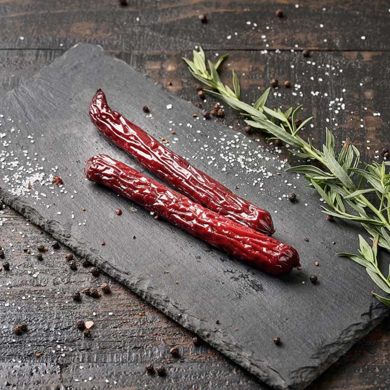 Two beef snack sticks on a stone platter