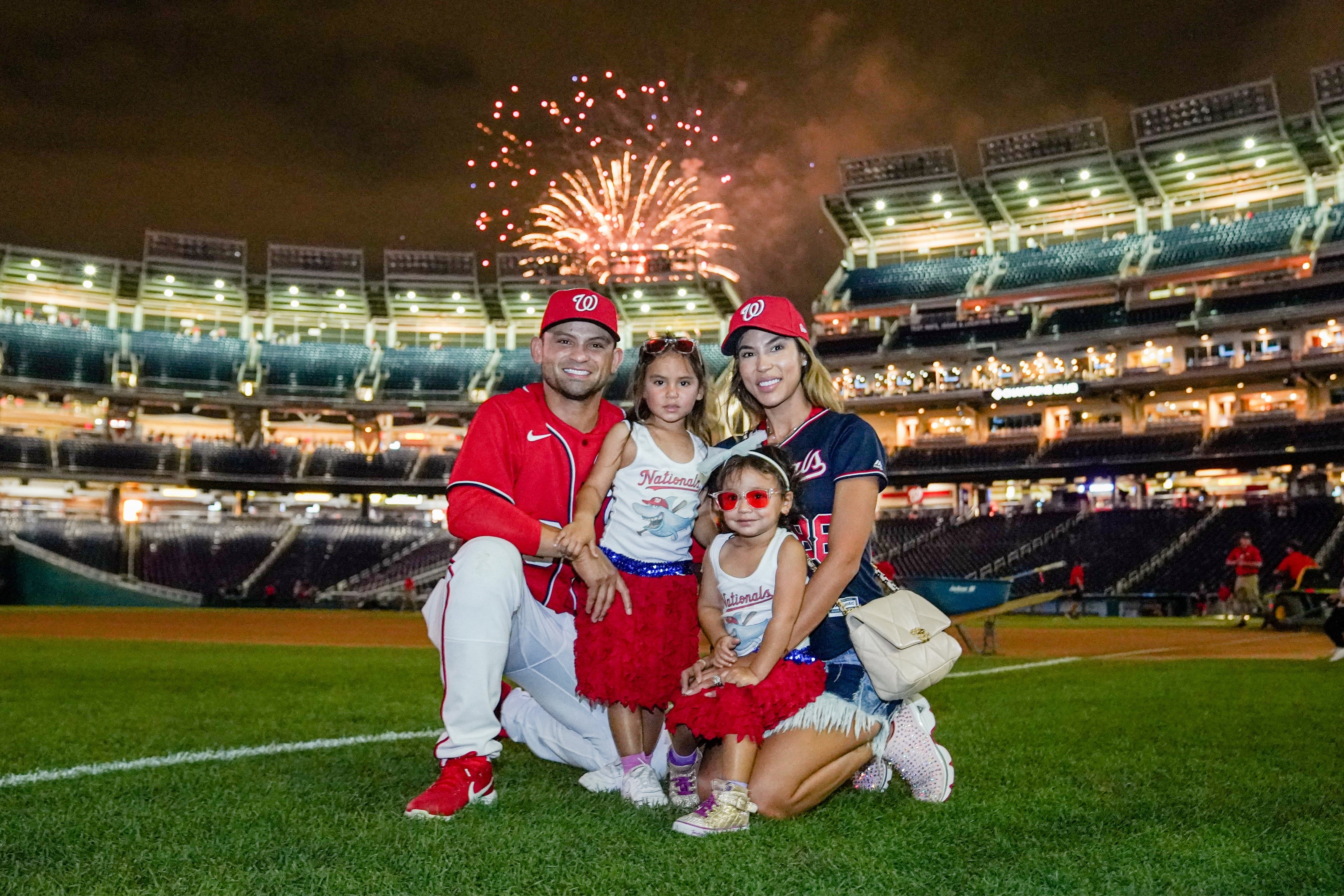 Gerardo Parra and his family posing on a baseball field with fireworks in the background