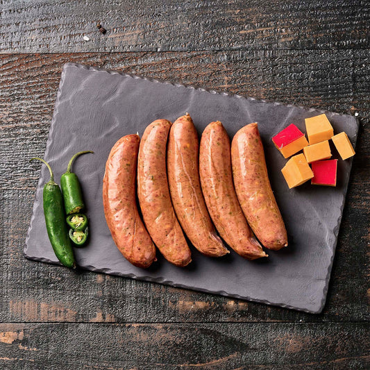 5 sausages on a slate board with peppers and cheese on a wooden background