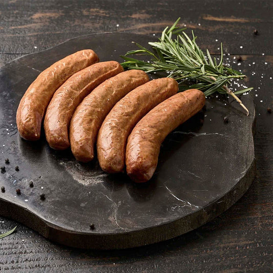 Five sausages on a dark stone plate with rosemary on a wooden background
