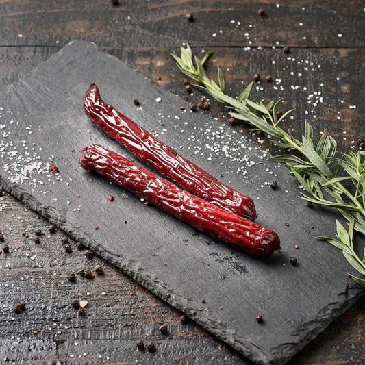 Two beef snack sticks on a stone platter
