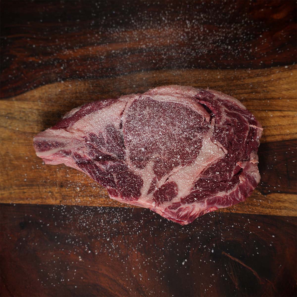 Raw steak on a wooden cutting board with a dark background